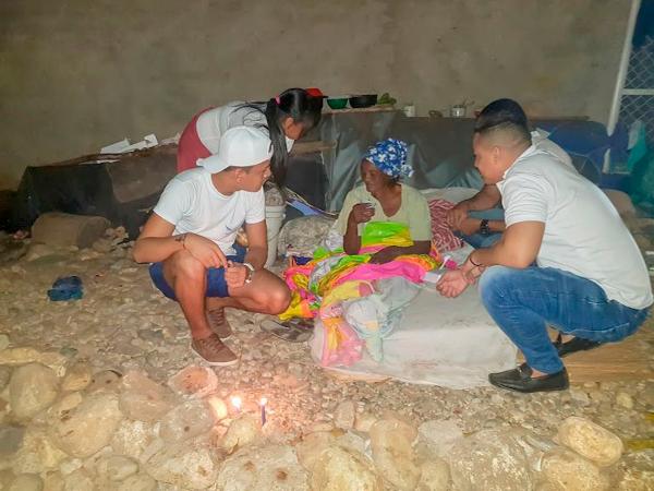 se muestra a miembros de la ong atendiendo a una señora mayor en la calle
